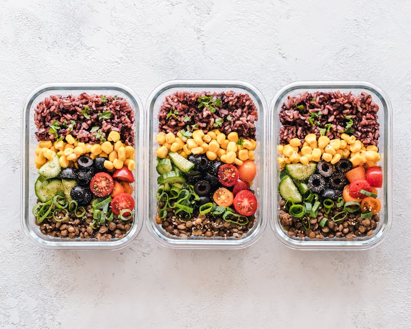 Colorful healthy meal prep with corn, olives, tomatoes, and lentils in glass containers.