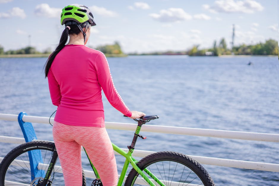 Back view of a woman cyclist by a lake enjoying the outdoors on a sunny day